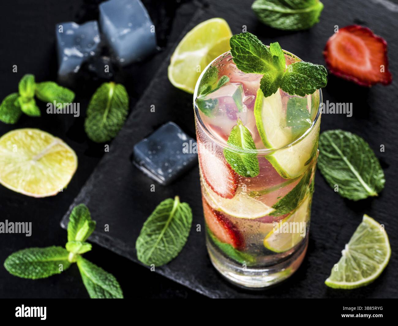 Limonata fresca con fragole, lime e menta su fondo in pietra scura. Bevanda estiva fredda alla fragola con menta e ghiaccio. Mojito di fragole in vetro e. Foto Stock