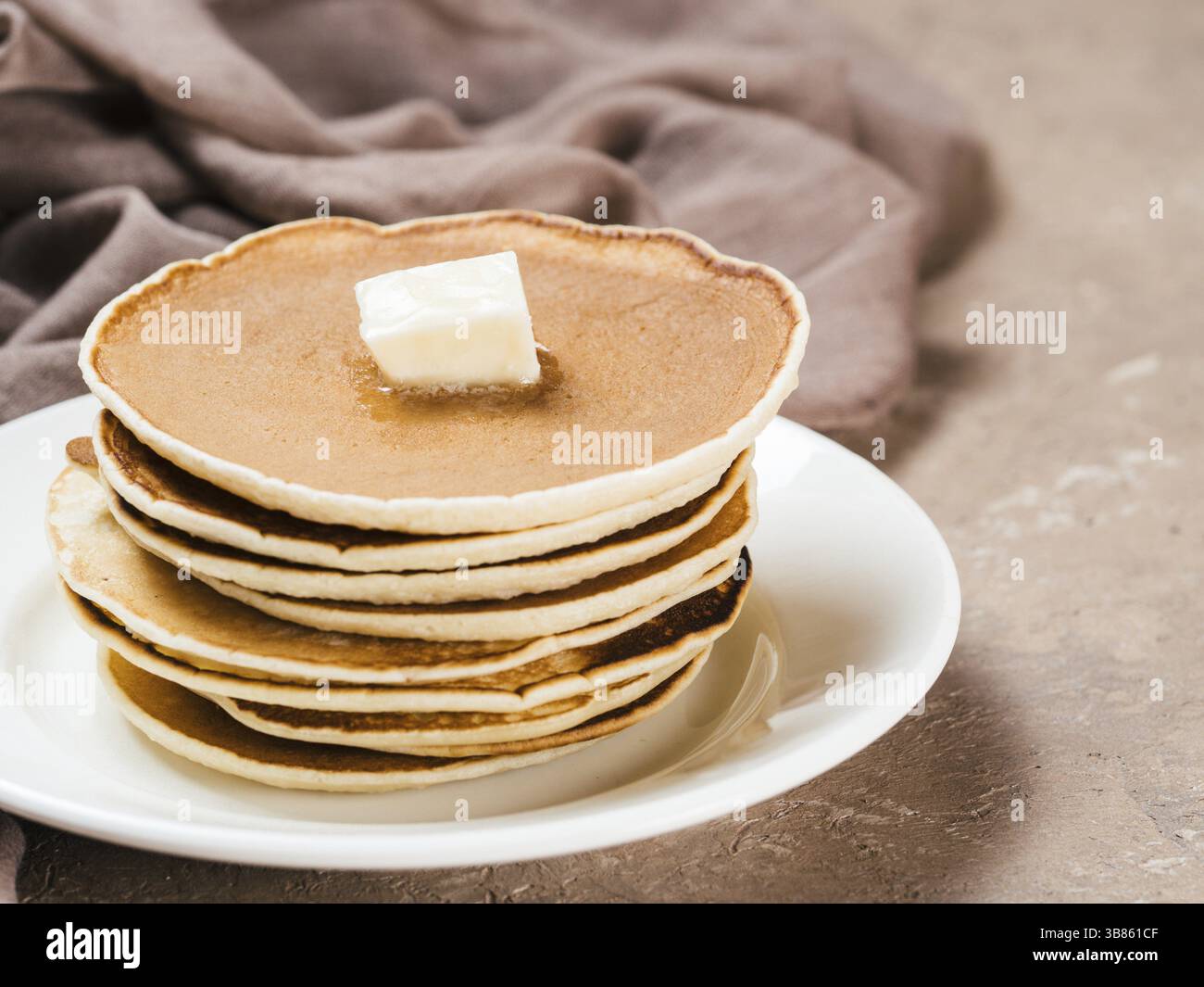 Vista ravvicinata dei pancake fatti in casa. Pila di pancake con burro su fondo marrone in cemento Foto Stock