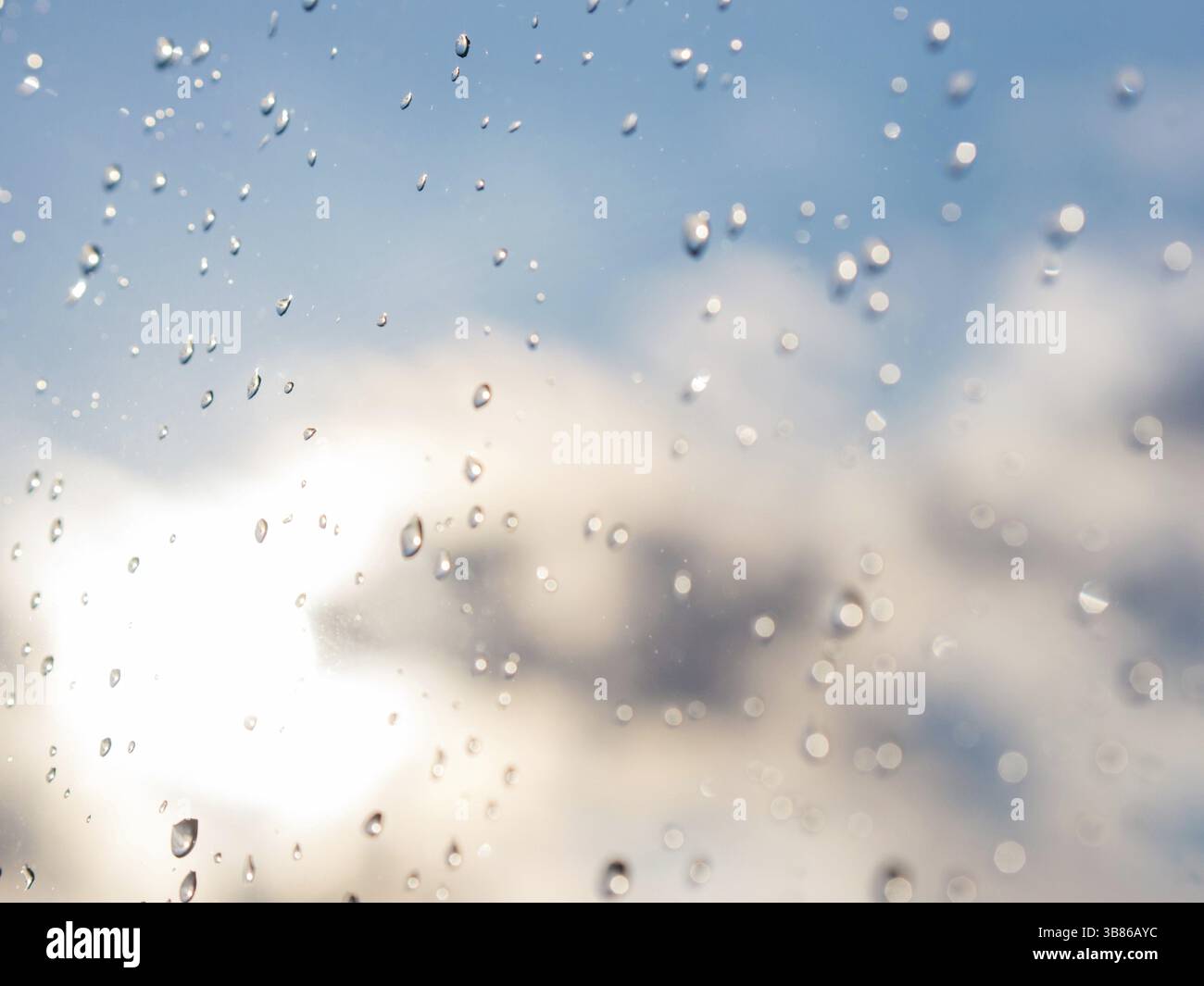 Gocce d'acqua di pioggia su sfondo in vetro blu. Pioggia cade sul finestrino. DOF poco profondo Foto Stock