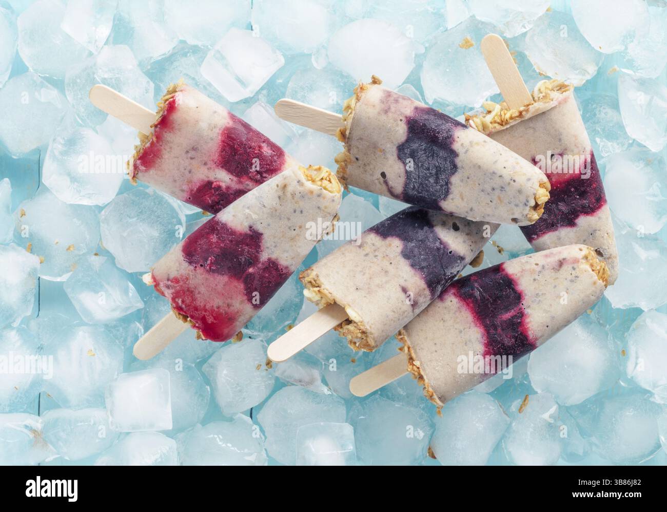 Gelato artigianale con frutti di bosco, muesli e semi di cia. Concetto di sana colazione estiva. Popsicle di yogurt e banana con frutti di bosco e. Foto Stock