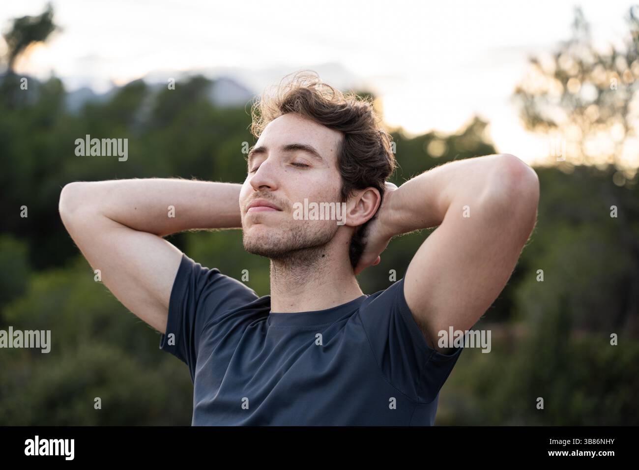 Un uomo respira aria fresca in natura. Stile di vita sano e benessere emotivo. Foto Stock
