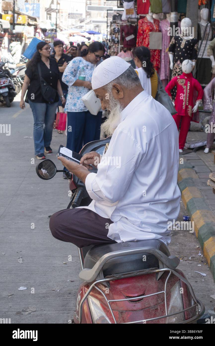 Uomo musulmano seduto a gambe incrociate in moto a Bangalore, Karnataka, India, Asia Foto Stock
