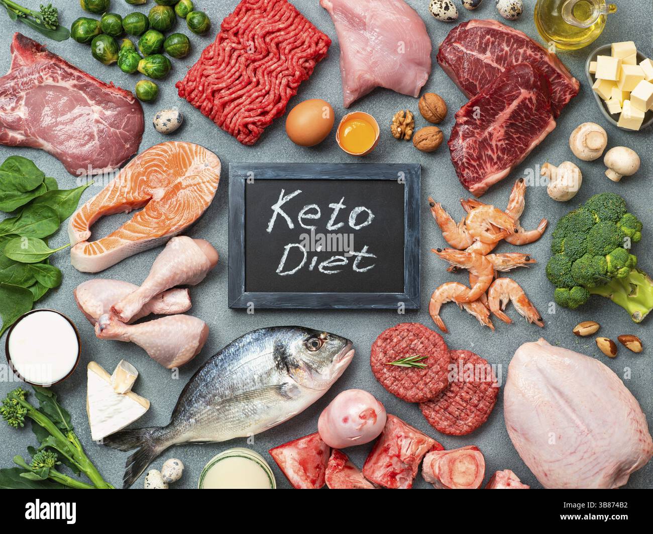 Dieta cheto concetto. Materie prime per la dieta povera di carboidrati - carne, pollame, pesce, frutti di mare, uova, carni bovine le ossa per il brodo di osso e parole cheto dieta su pietra grigia Foto Stock