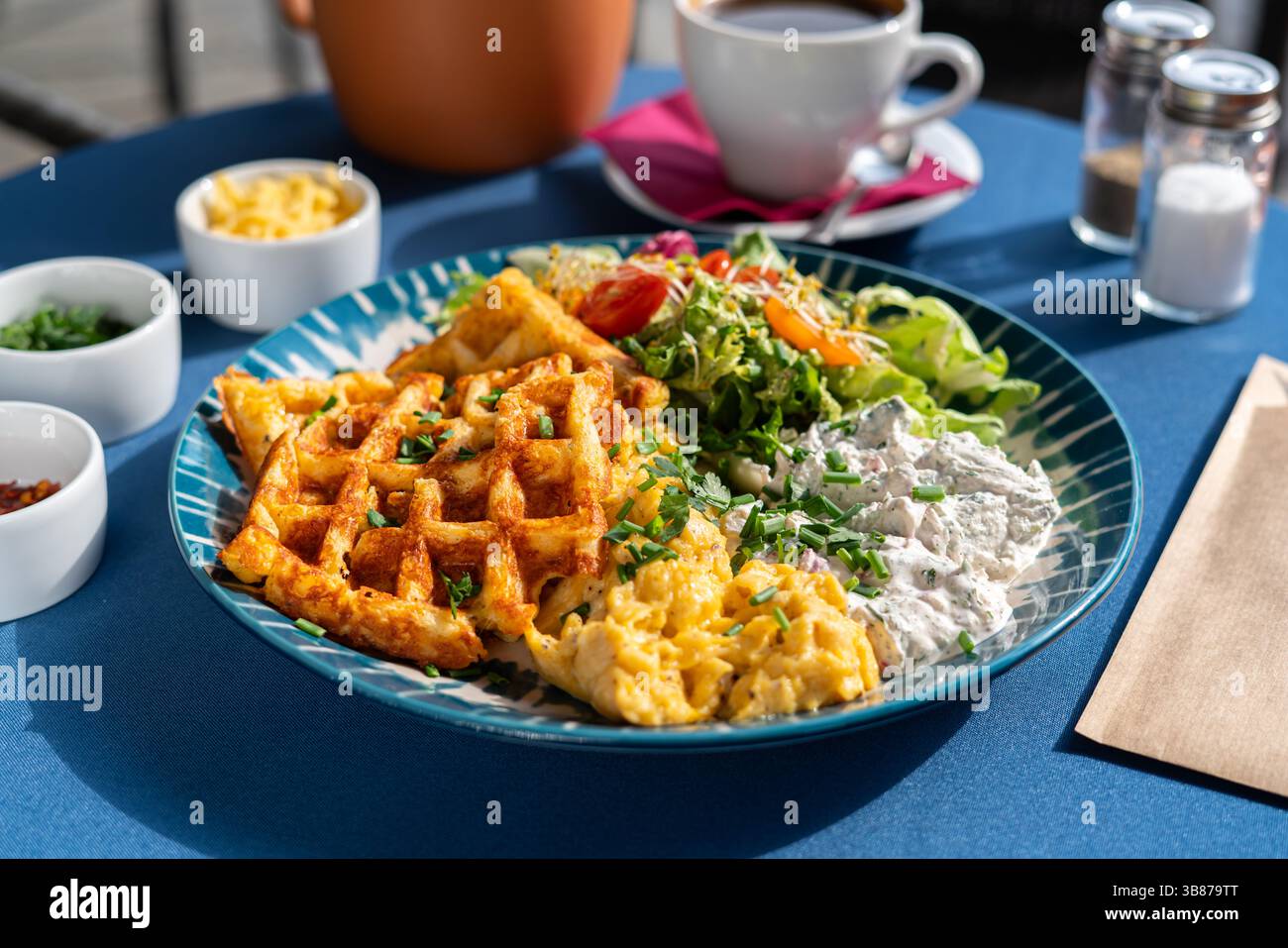 Waffle con uova strapazzate e formaggio fresco bianco serviti con verdure e verdure su un piatto splendidamente decorato, un set per la colazione, Foto Stock