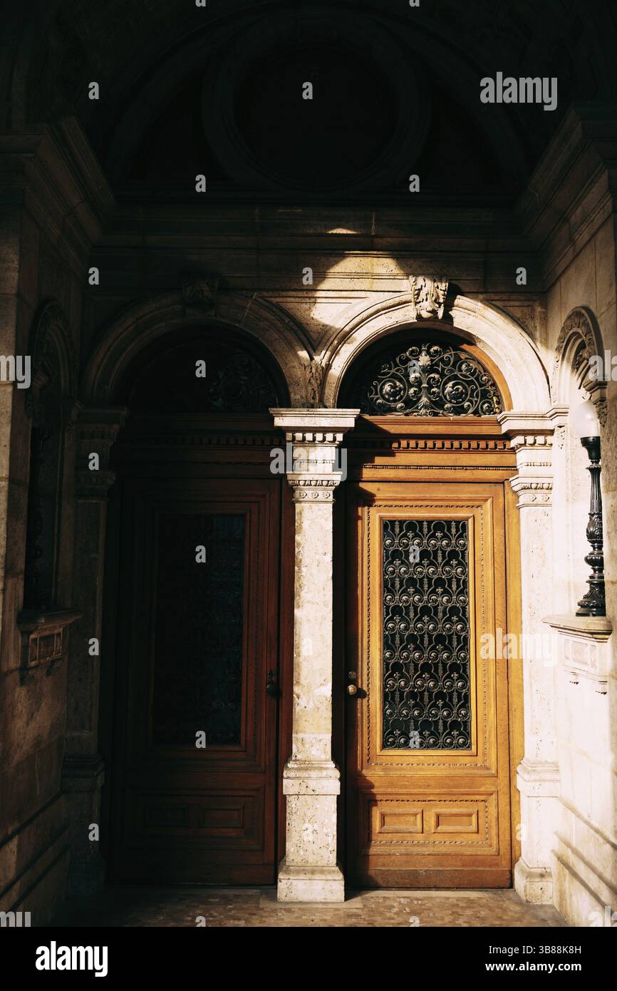 Due porte d'ingresso marroni con grandi vetrate e barre negli archi tra le colonne. Foto Stock
