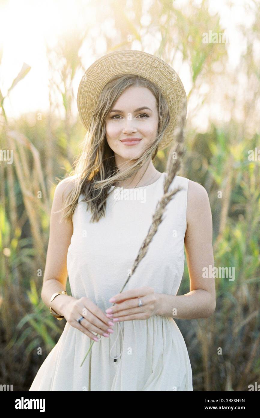 La ragazza con un cappello di paglia sta con un bastone asciutto in mano. Foto Stock