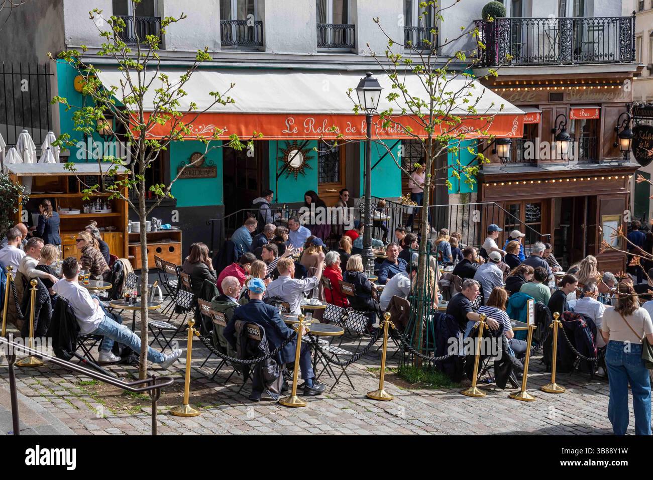 Persone sulla grande terrazza marciapiede di le Relais de la Butte con posti a sedere all'aperto al numero 12 di Rue Ravignan nel quartiere Montmartre di Parigi, Francia Foto Stock