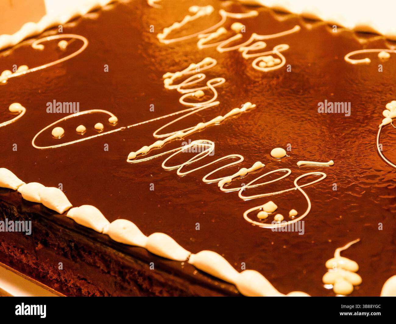 Primo piano di una torta nuziale glassata al cioccolato con scritto "vive les mariés", che celebra un matrimonio in stile francese. Foto Stock