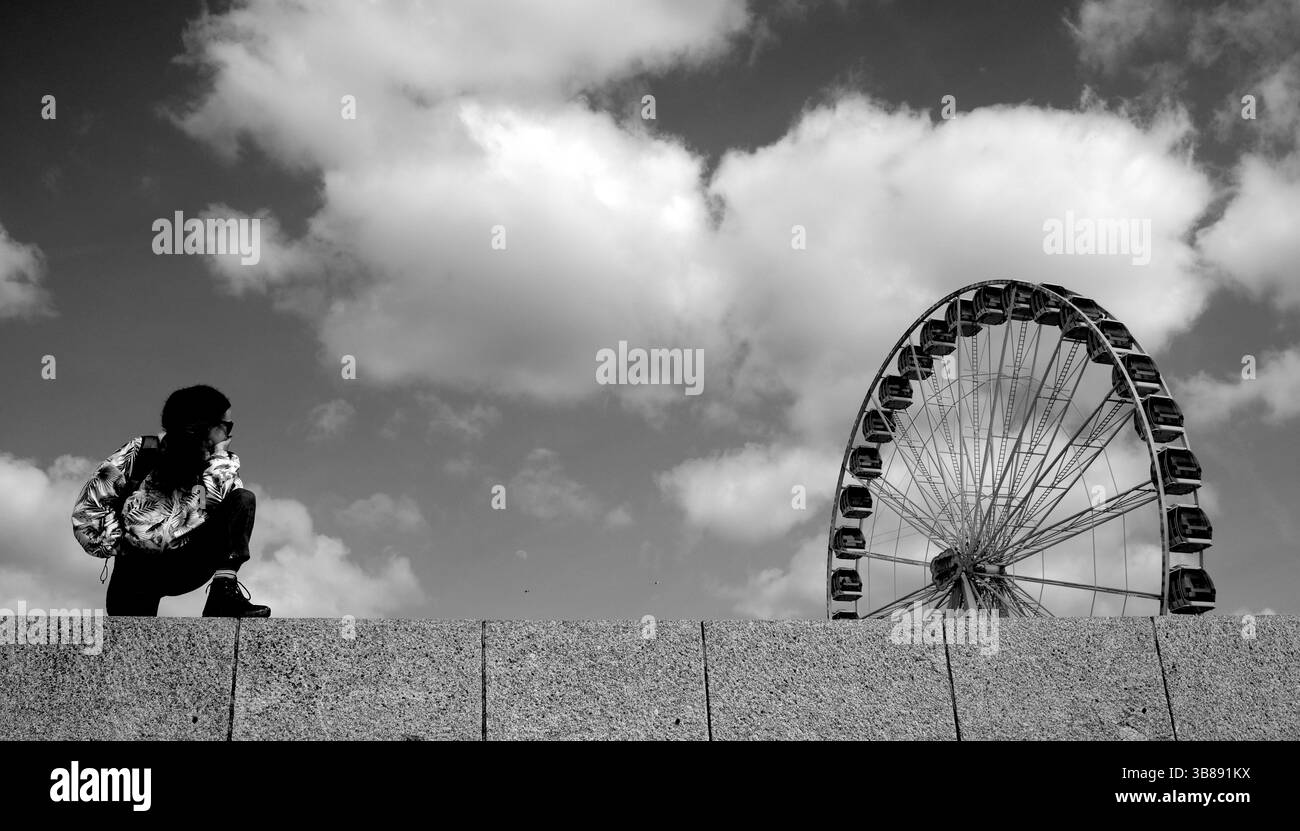 Berck-sur-Mer o Berck nel nord della Francia, con la grande ruota della fiera e una giovane donna che guarda al mare. Foto Stock