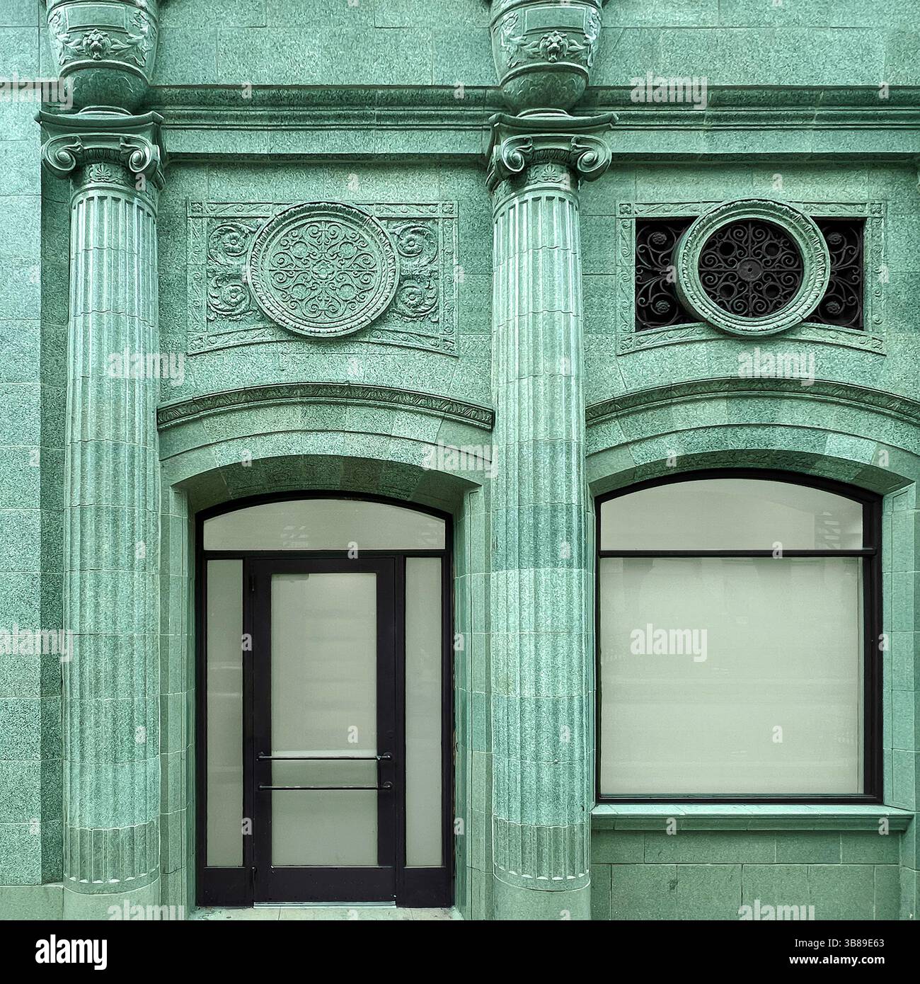 Elegante facciata in pietra verde con colonne classiche, finestre ad arco e intricati ornamenti circolari in un edificio storico di Chicago Foto Stock
