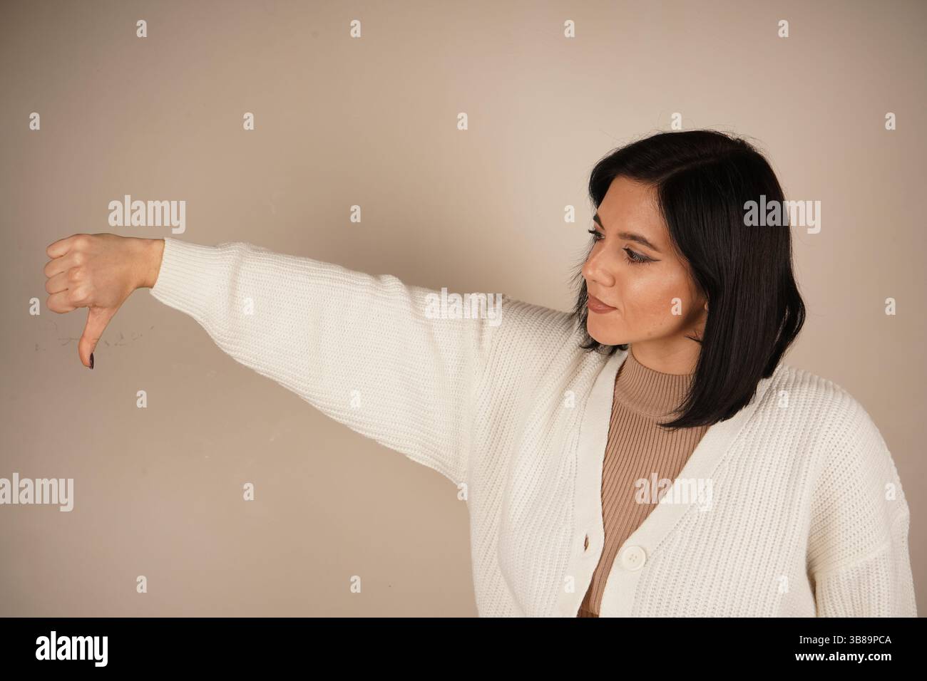 Donna seria che mostra un doppio gesto verso il basso, esprimendo delusione. La sua espressione focalizzata enfatizza l'emozione dell'antipatia. Un messaggio chiaro Foto Stock