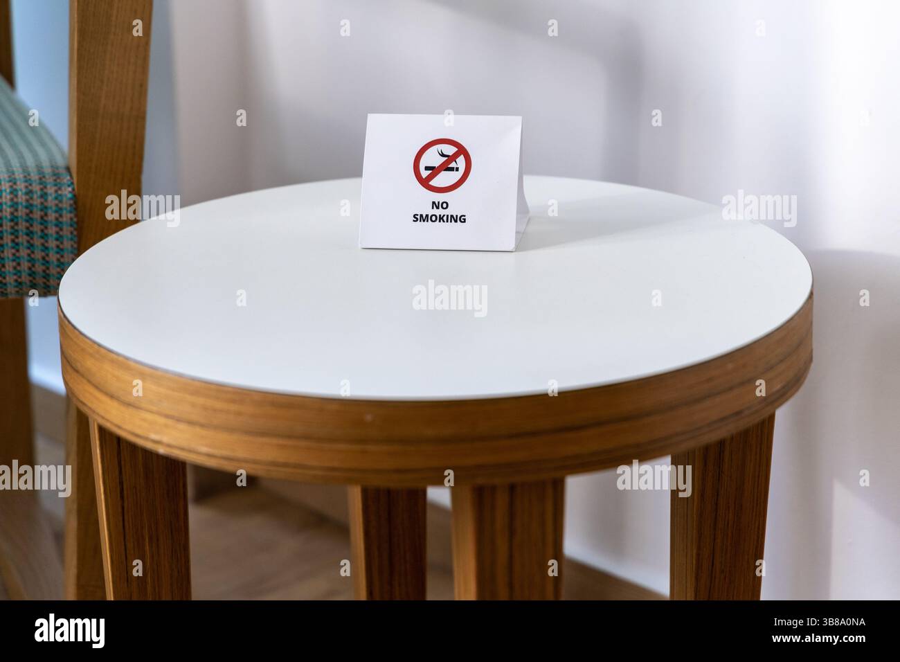 Semplice ed efficace cartello non fumatori visualizzato su un moderno tavolo bianco in una camera ben illuminata. Foto Stock