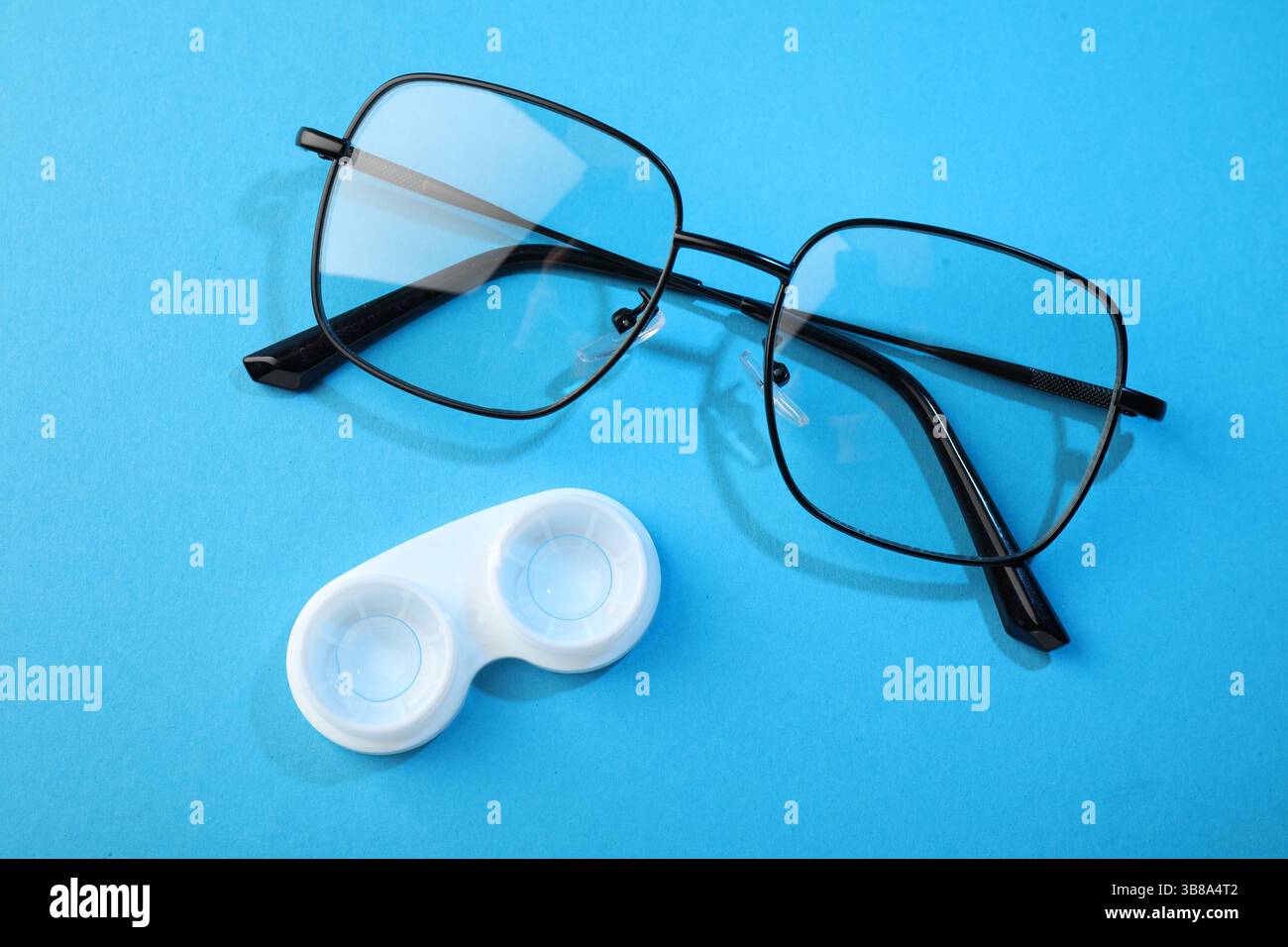 Lenti a contatto in astuccio e occhiali su sfondo blu, piatto Foto Stock