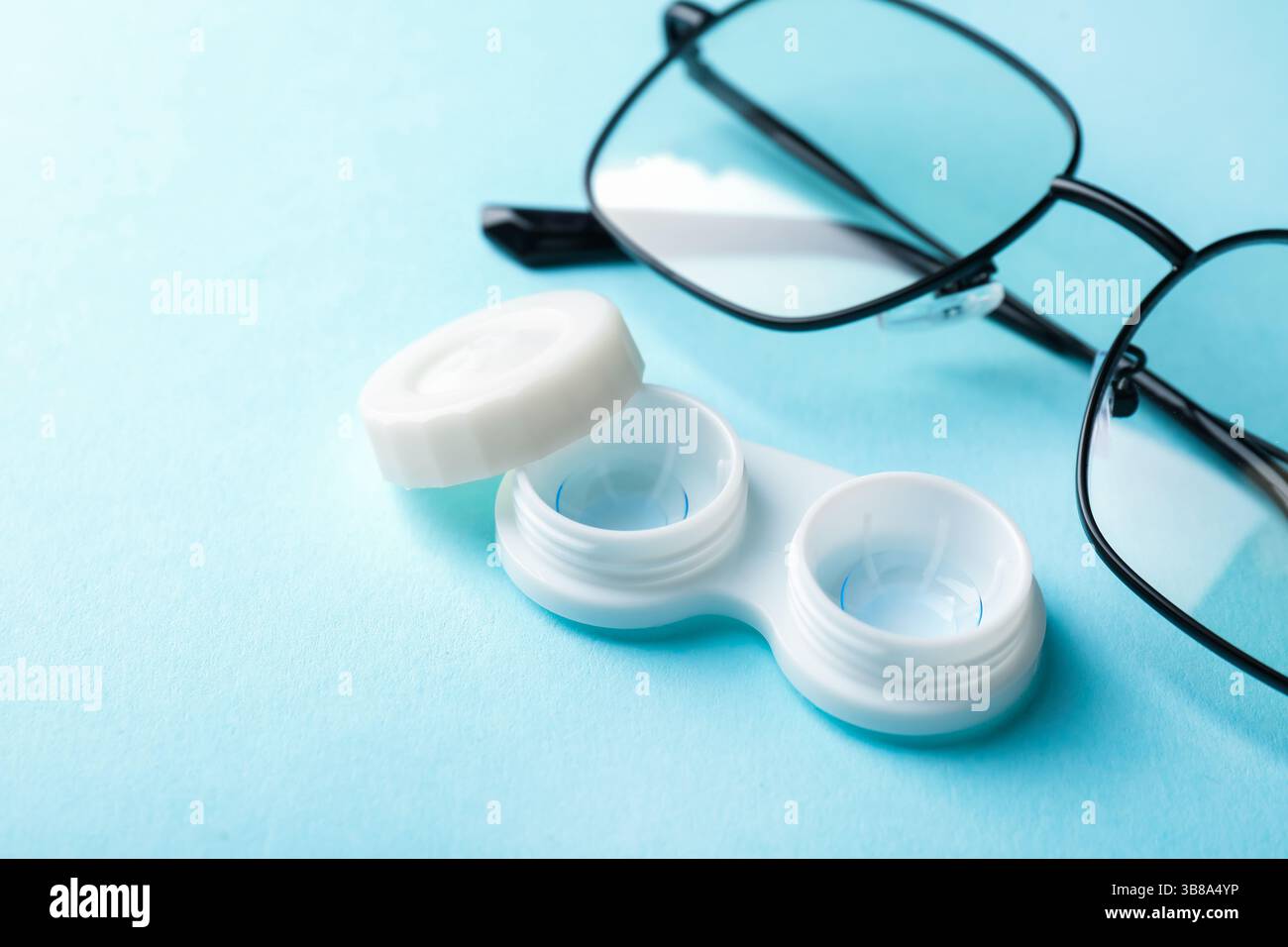 Lenti a contatto nella custodia e occhiali su sfondo azzurro, primo piano Foto Stock