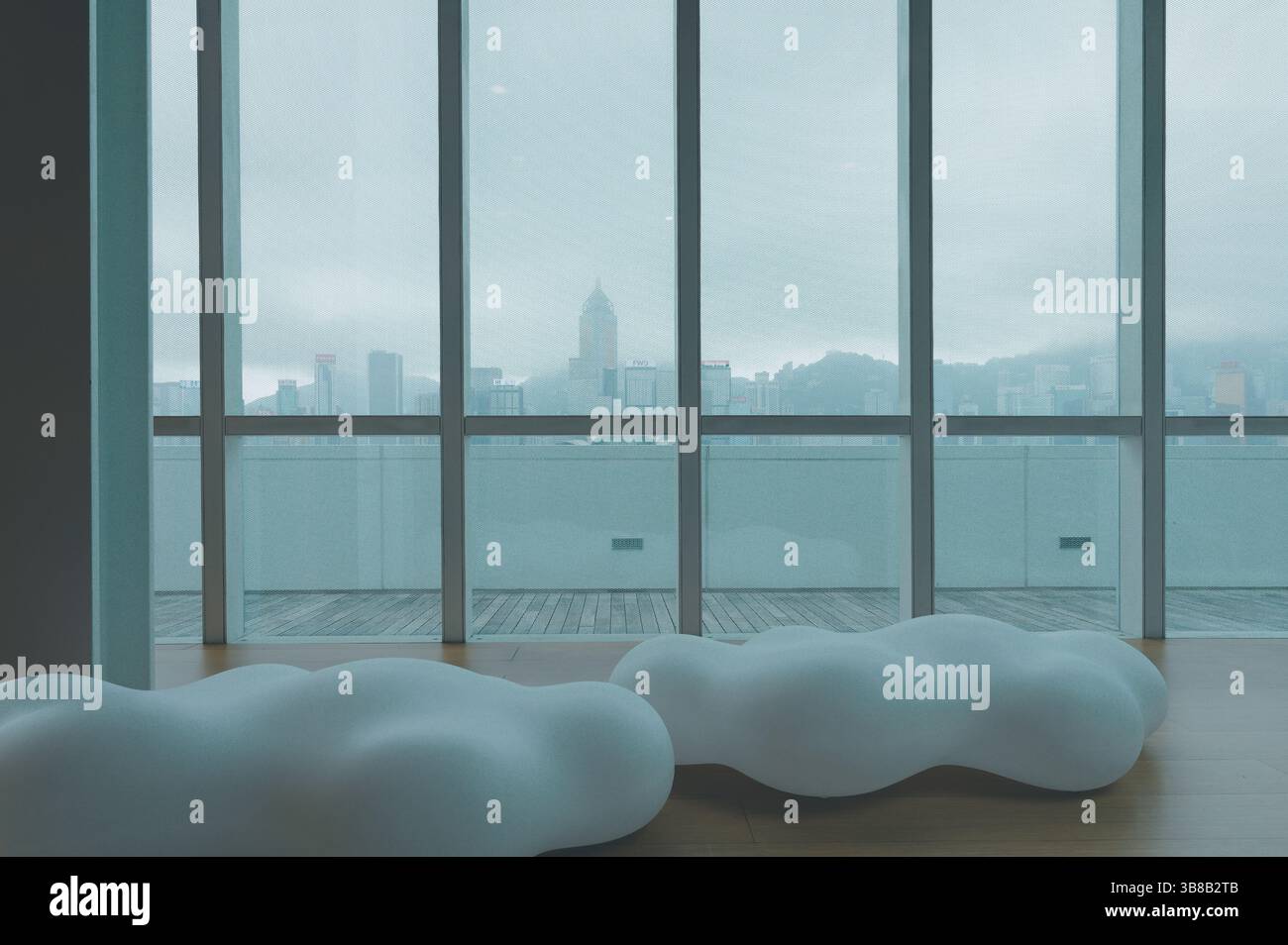 I posti a sedere a forma di nuvola poggiano sullo sfondo di uno skyline nebbioso di Hong Kong presso l'HKMoA Foto Stock