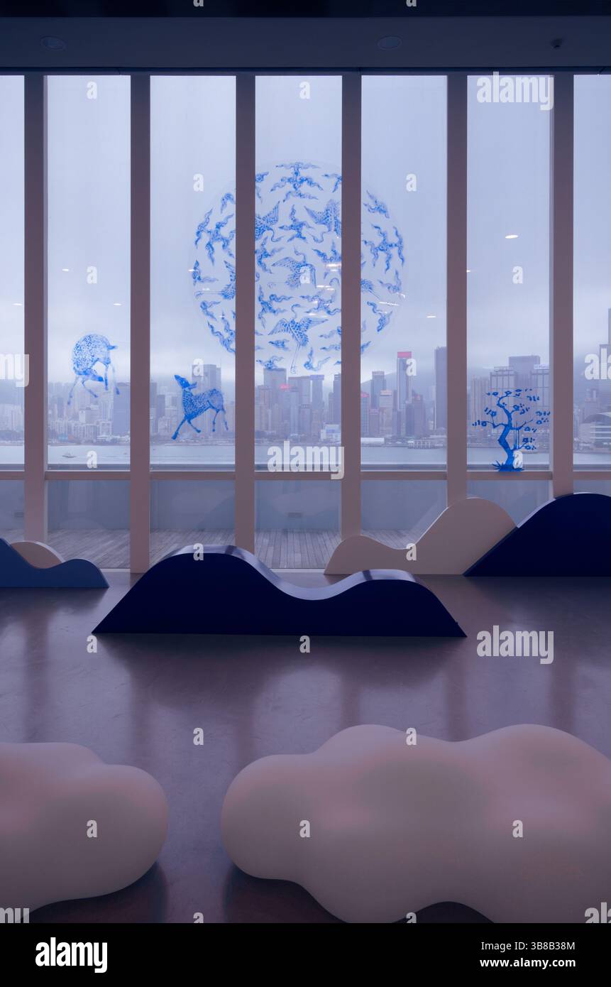 Installazione artistica presso l'HKMoA, posti a sedere a forma di nuvola e forme ondulate contro uno skyline nebbioso e motivi di animali blu Foto Stock