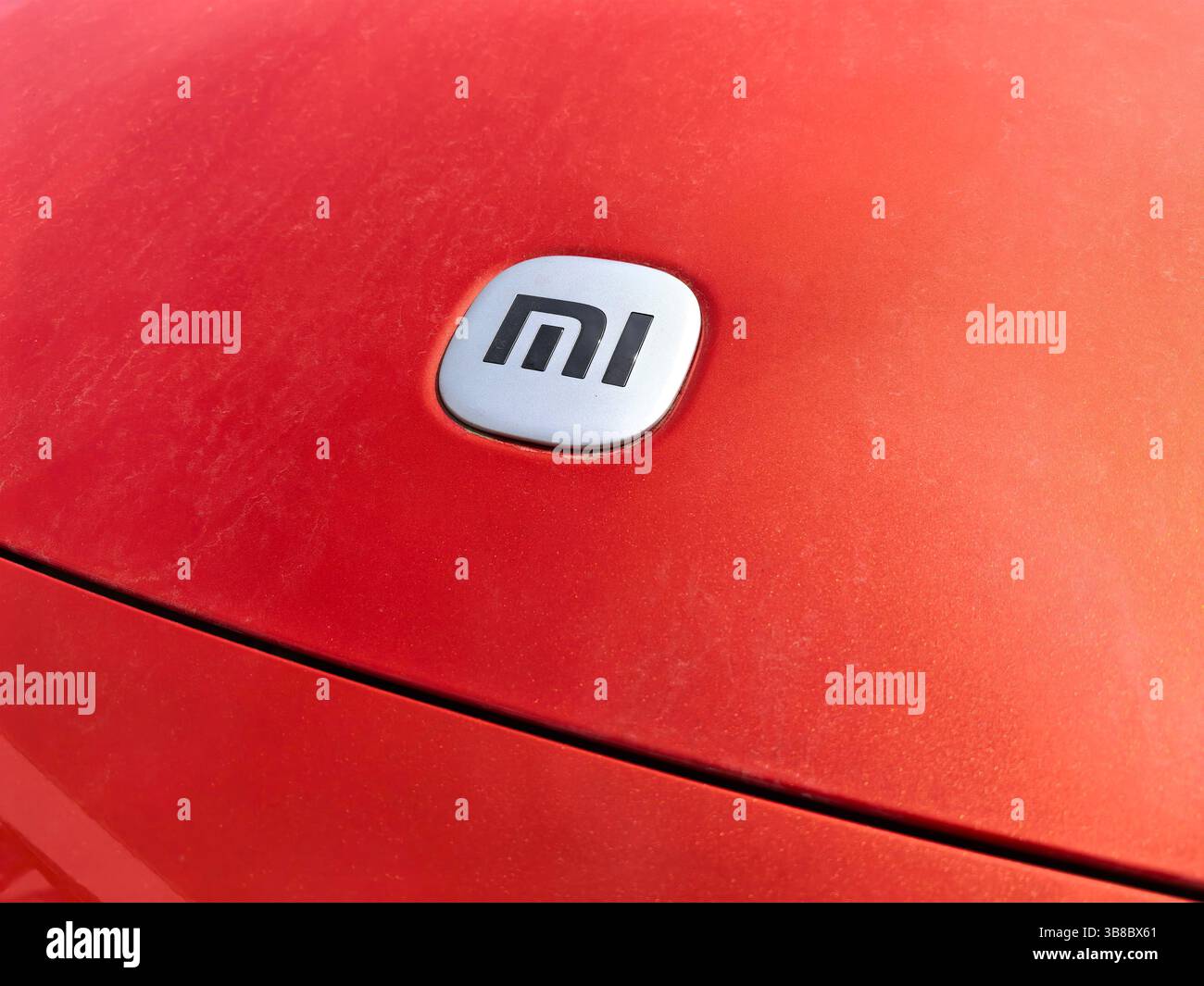 Minsk, Bielorussia - 28 aprile 2025: Il cofano rosso brillante cattura la luce del sole mentre spicca l'emblema distintivo. La polvere copre leggermente la superficie, aggiungendo un Foto Stock