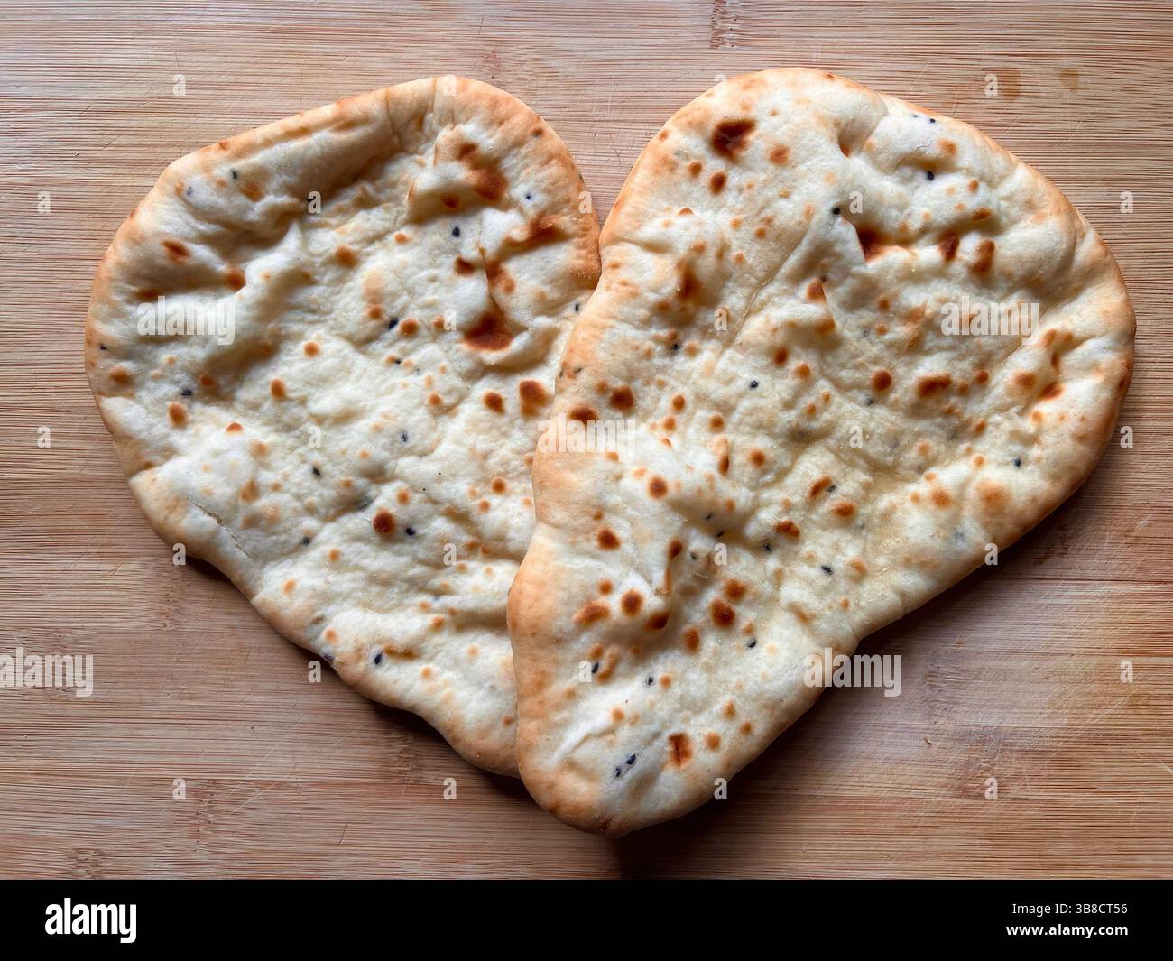 Due Naan indiani a forma di cuore d'amore su una tavola di legno. Foto Stock