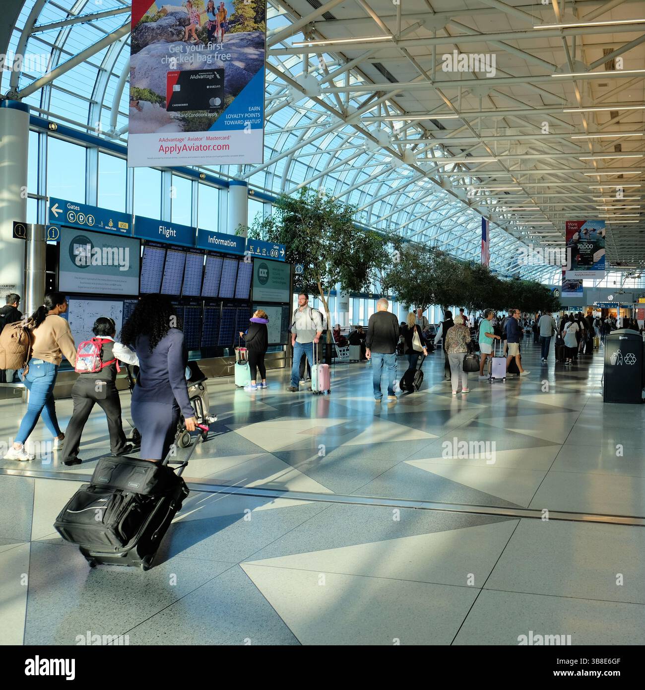 Corridoio di collegamento con i viaggiatori e i monitor delle informazioni di volo; aeroporto internazionale Douglas di Charlotte; Charlotte, North Carolina. Foto Stock