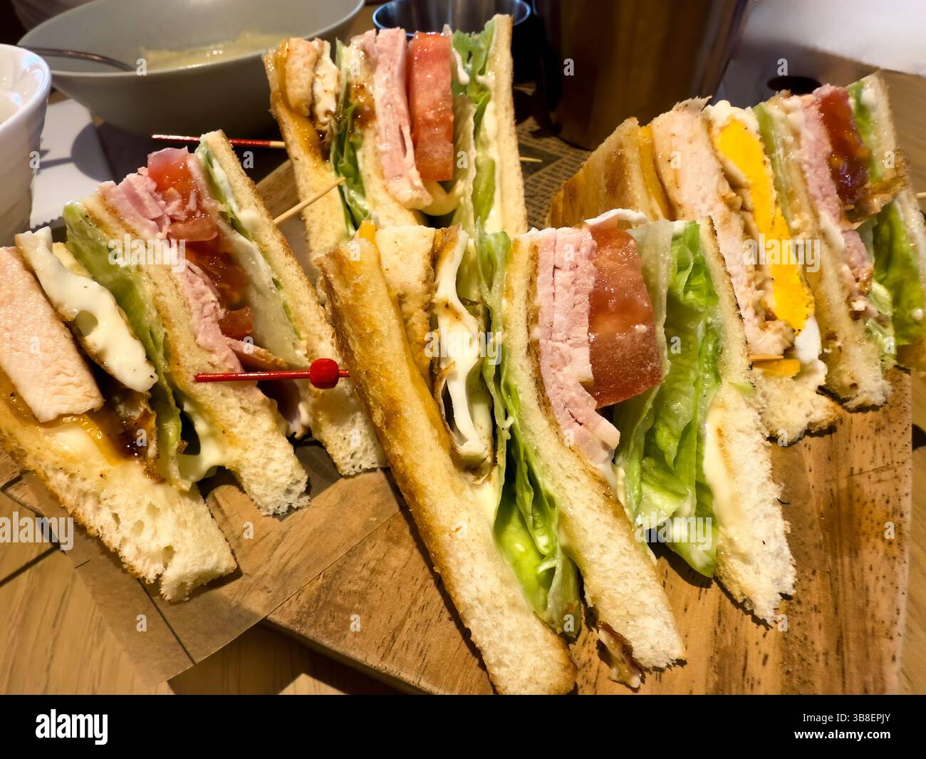 Vista ravvicinata del Club sandwich sul tavolo da portata con ciotola per zuppe sullo sfondo Foto Stock