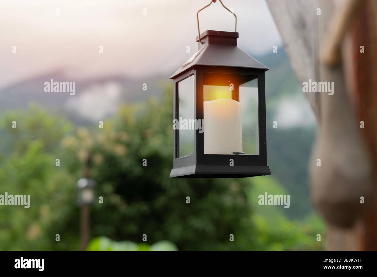 Lanterna decorativa a lume di candela appesa su un albero in giardino con luce solare e sfondo naturale. Garden Lanterns Home Decoration Concept. Foto Stock