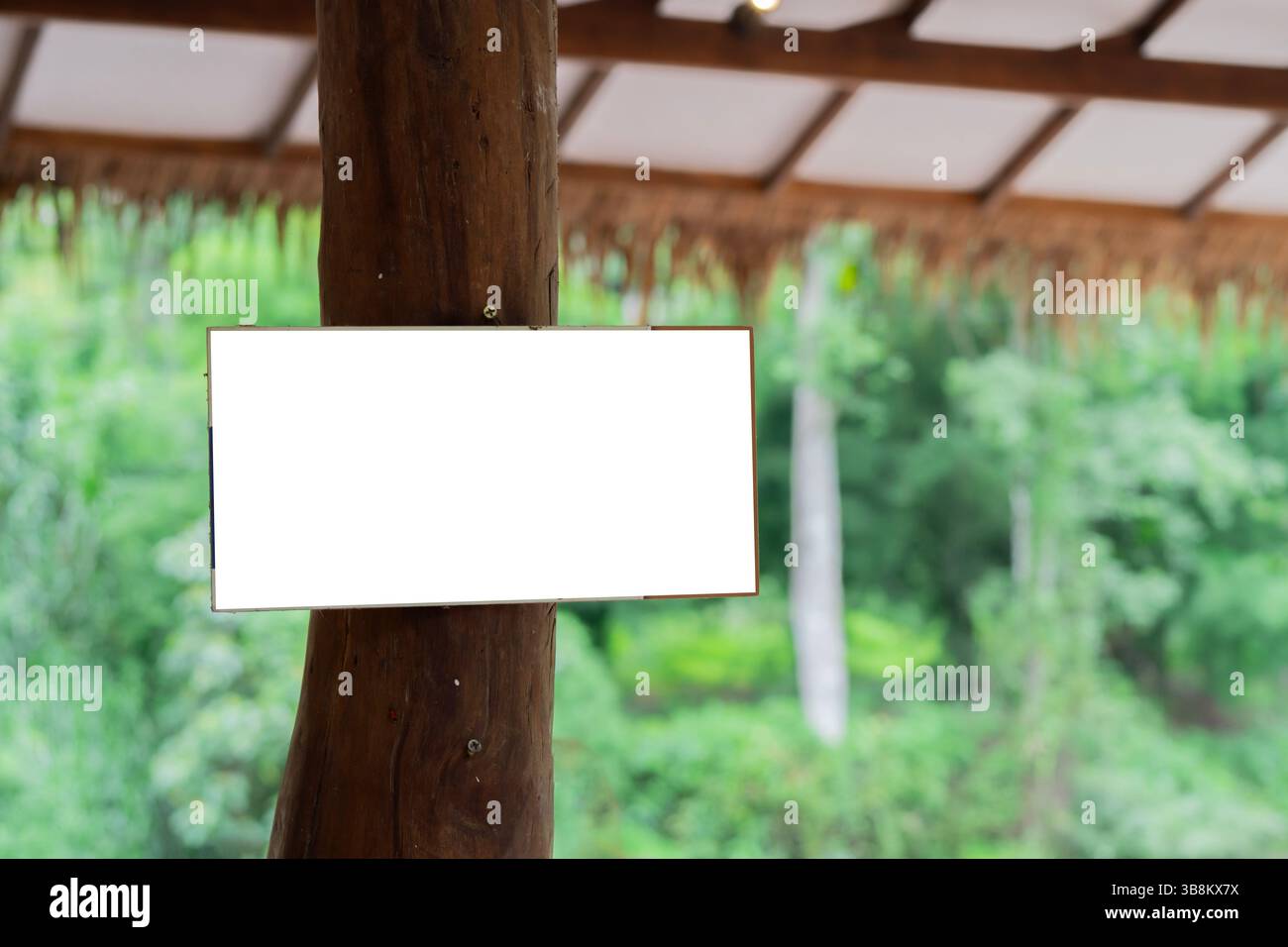 Cartello di legno vuoto installato su un grande palo di legno sotto il tetto. Tropical Cafe o mockup con l'insegna dell'hotel Foto Stock