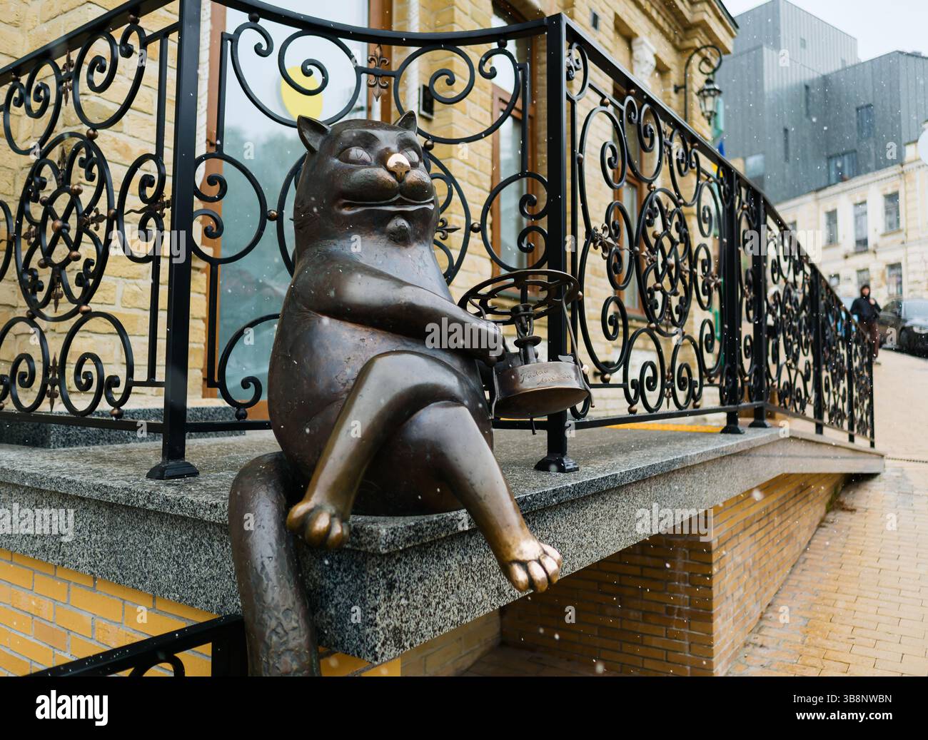 Kiev, Ucraina - 7 aprile 2025: Il gatto di bronzo all'ingresso del Museo Mikhail Bulgakov sulla discesa di Andrijivskyy durante una nevicata leggera Foto Stock