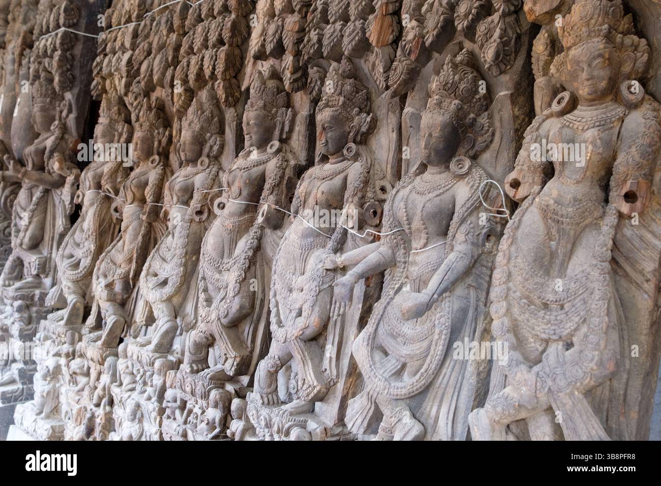 Antiche sculture in pietra di ballerini celesti, o apsaras, adornano un muro del tempio, mostrando arte e devozione tradizionali. Foto Stock