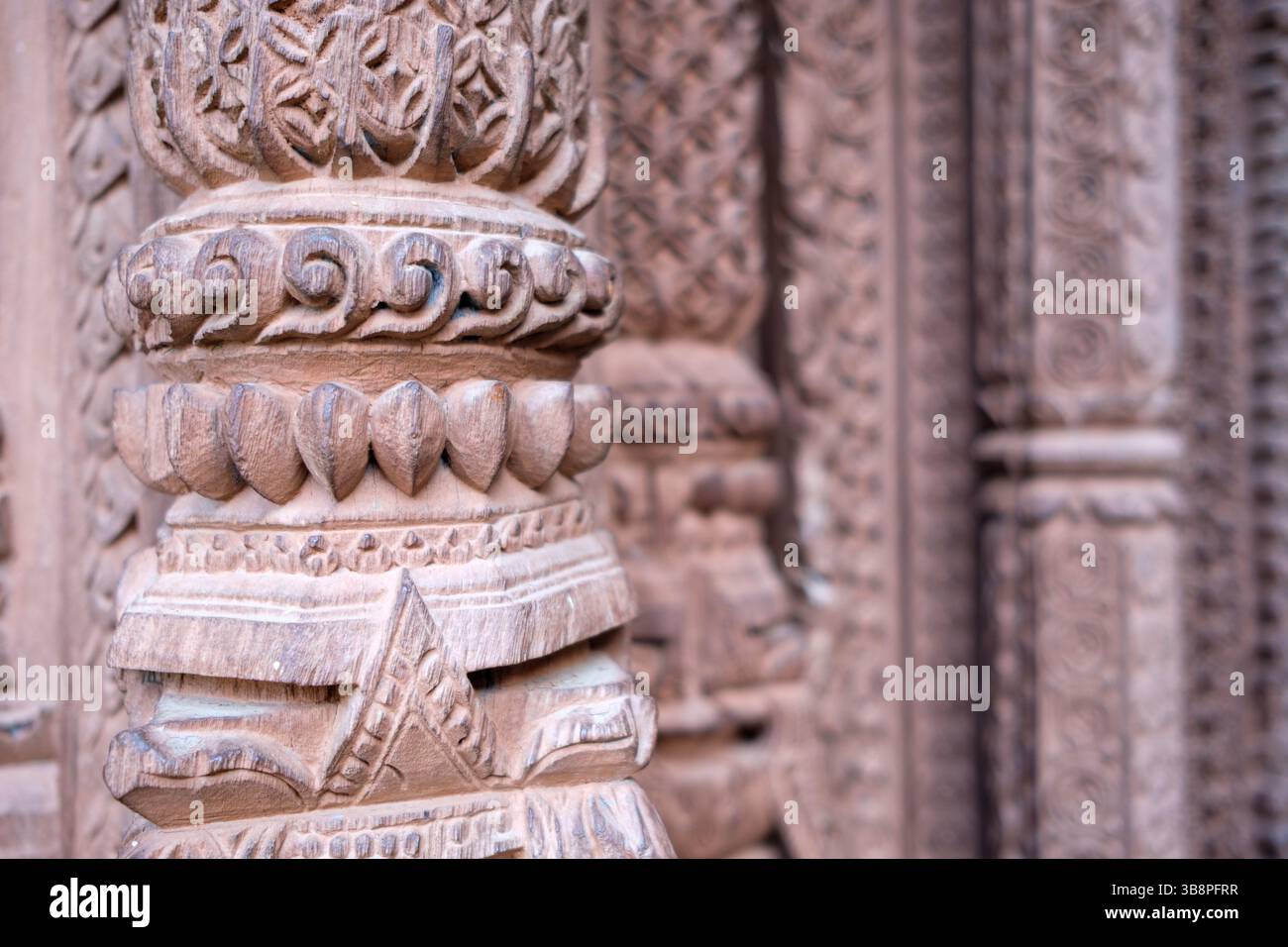 Intricate sculture in legno adornano una colonna del tempio, mostrando artigianato tradizionale e patrimonio culturale. Foto Stock