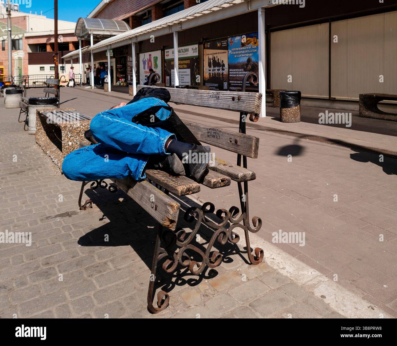 Kiev, Ucraina - 1 maggio 2025. Nel cuore della città, una persona riposa su una panchina, incarnando la resilienza della vita quotidiana durante i continui tumulti mentre le strade roneggiano di attività. Foto Stock