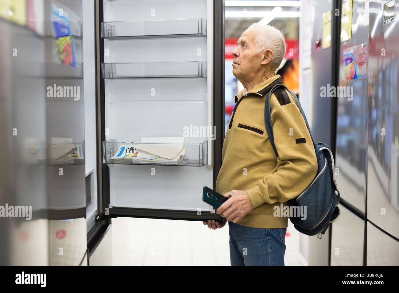 Pensionato Senor MAN che acquista un frigorifero nello showroom del negozio di elettrodomestici Foto Stock