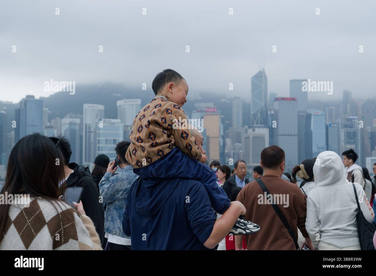 Padre e figlio condividono un momento di gioia con vista sullo skyline dell'Isola di Hong Kong Foto Stock