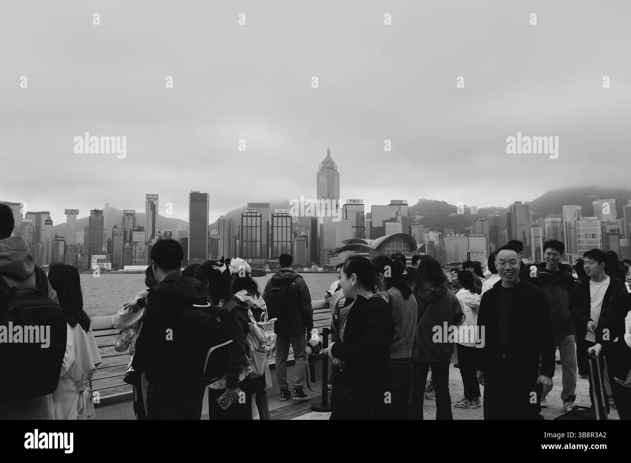 La folla si riunisce lungo la passeggiata per ammirare lo skyline attraverso Victoria Harbour verso l'isola di Hong Kong Foto Stock