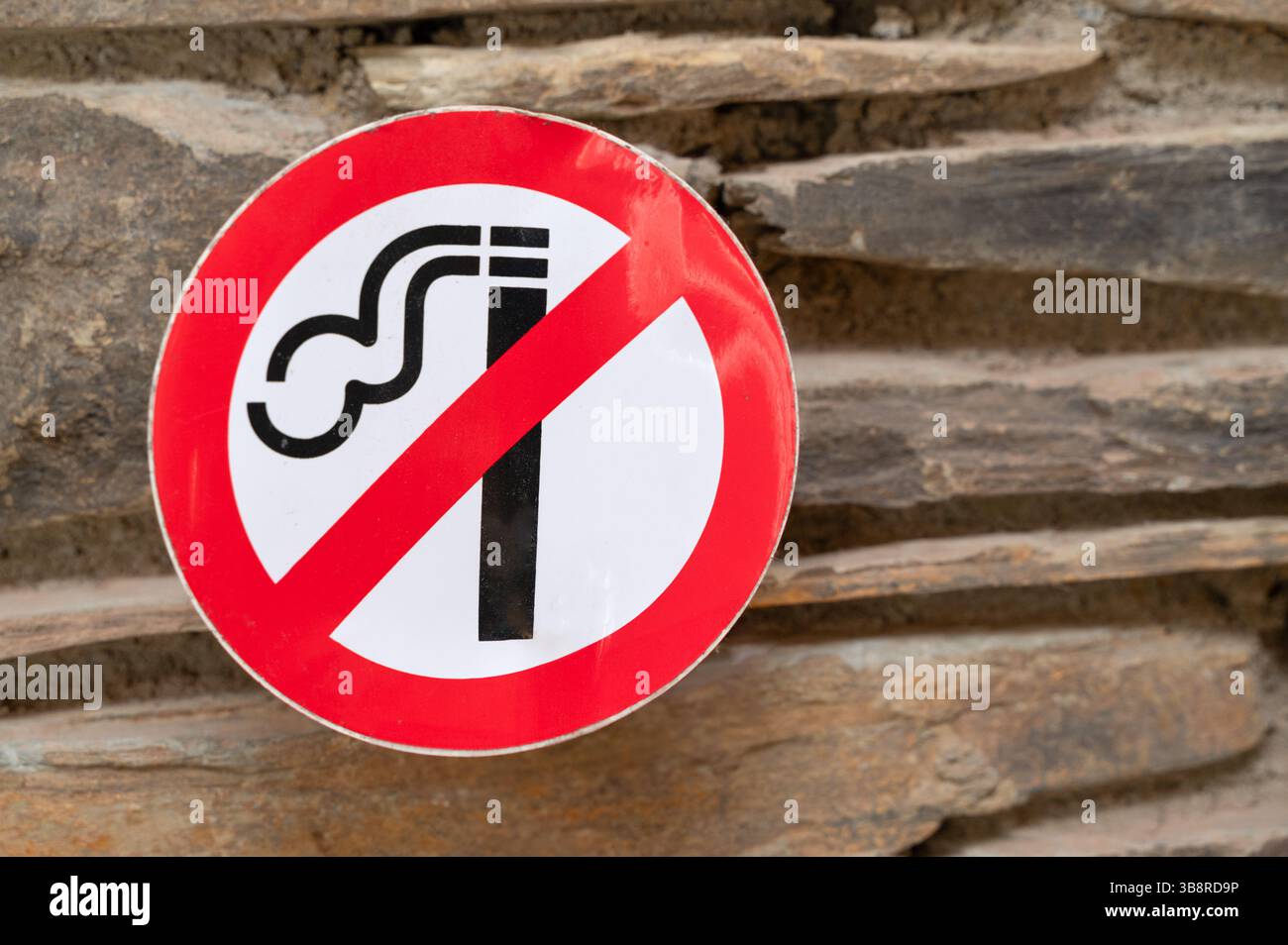Un importante cartello di divieto di fumo esposto su un muro di pietra robusto per la consapevolezza e la salute del pubblico Foto Stock