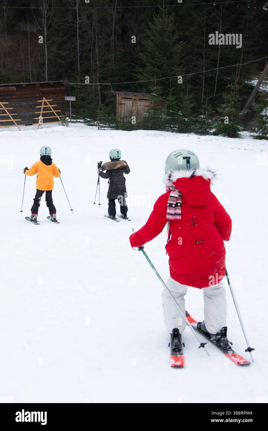 I bambini possono godersi una giornata di sci, con abiti colorati e luminosi che contrastano con la neve incontaminata. La risata risuona nell'atmosfera tranquilla come loro Foto Stock