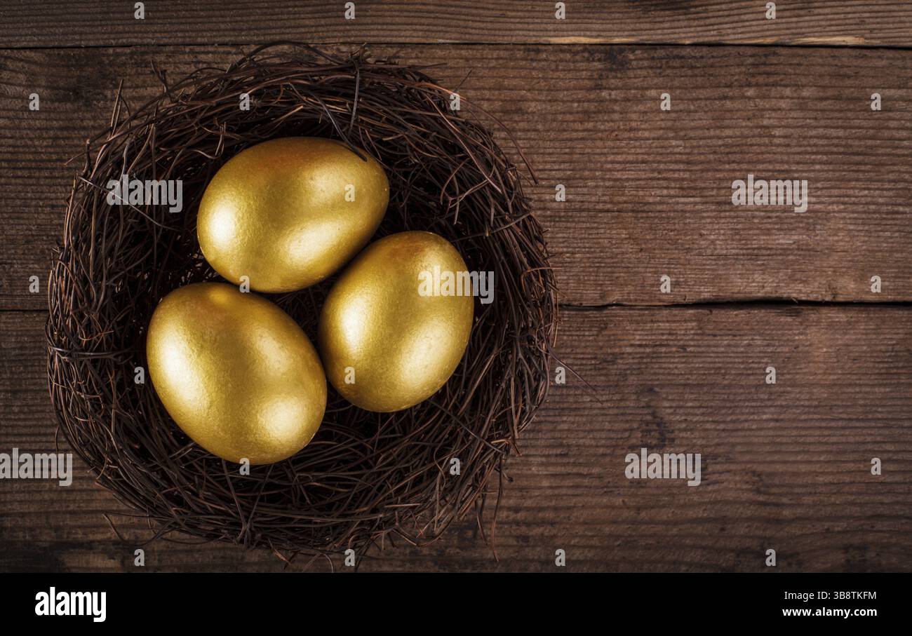 Uova d'oro nel nido su sfondo di legno con copia del testo Foto Stock