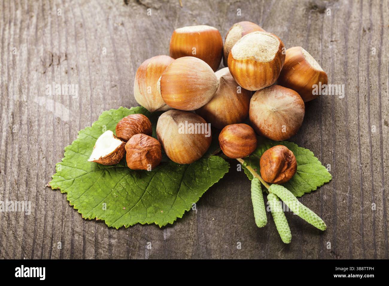 Le nocciole con guscio e foglia verde sul tavolo di legno Foto Stock