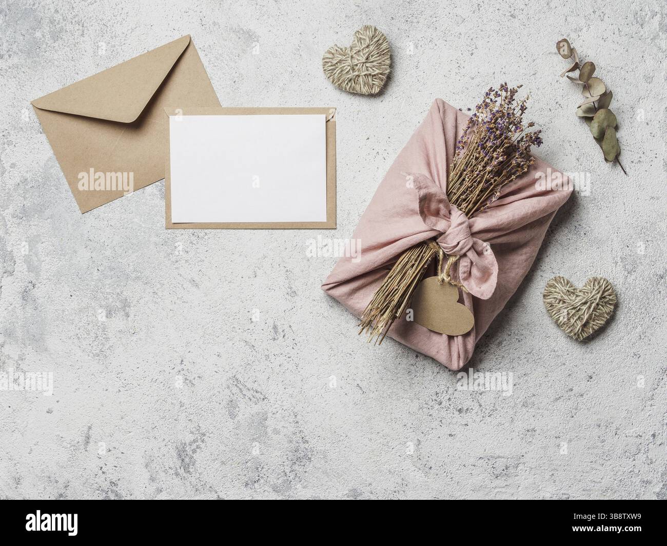 Zero rifiuti San Valentino concetto e mock up. Confezione di panni eco-friendly in stile Furoshiki, busta di carta artigianale, regalo vuoto o auto di auguri Foto Stock
