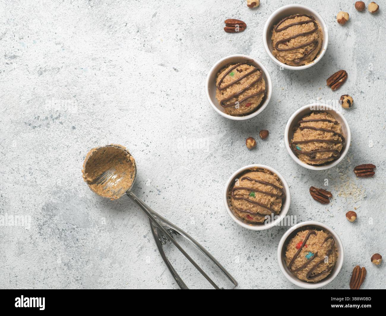 Di sicuro a mangiare materie monster pasta biscotto nella porzione piccola ciotola, gelato scoop e dadi sul cemento grigio Sfondo. Le idee e le ricette per i bambini e per bambino Foto Stock