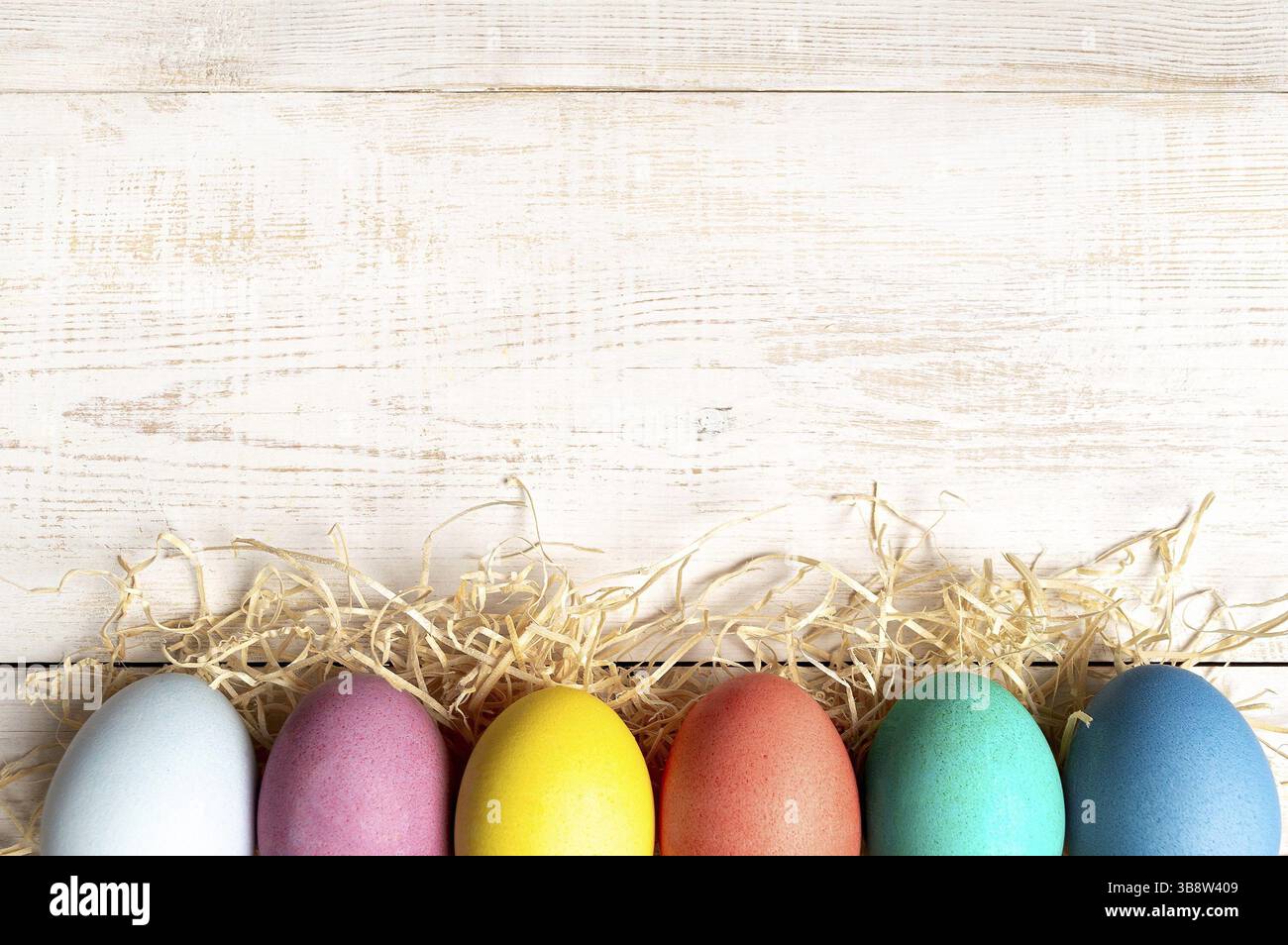 Concetto di Pasqua. Uova colorate su sfondo di legno bianco con spazio per la copia del testo. Vista dall'alto verso il basso o piatto Foto Stock