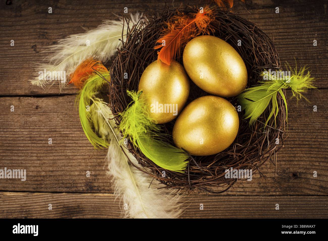 Uova d'oro nel nido su sfondo di legno con copia del testo Foto Stock