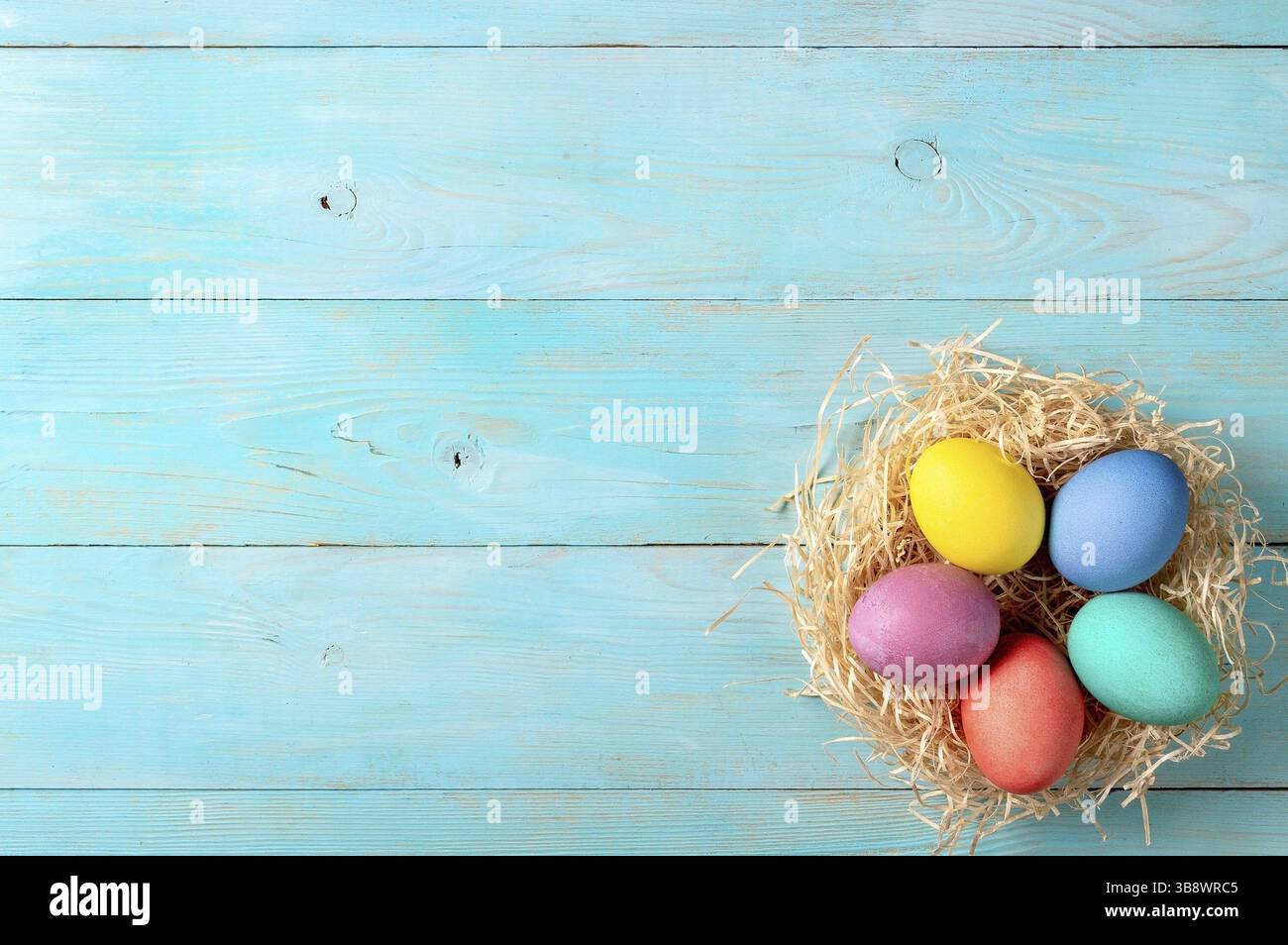 Concetto di Pasqua. Uova colorate su sfondo di legno blu con spazio di copia per il testo. Vista dall'alto verso il basso o piatto Foto Stock