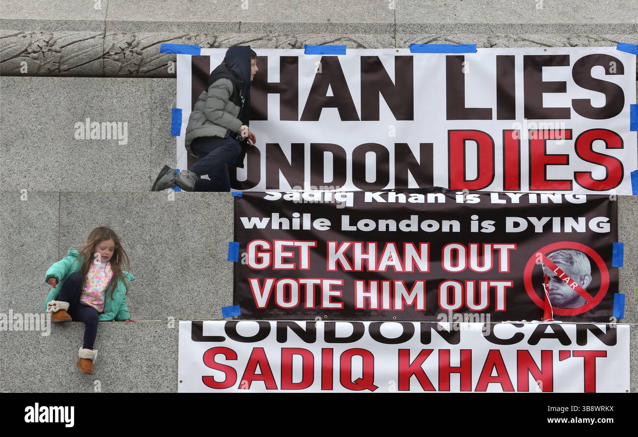 27 aprile 2024, Londra, Regno Unito: I manifestanti lasciano un paio di bambini a giocare accanto ai loro grandi striscioni che criticano Sadiq Khan durante la manifestazione. I manifestanti si riuniscono a Trafalgar Square a Londra per protestare contro il sindaco, la zona a bassissima emissione (ULEZ) di Sadiq Khan. Fu introdotto per la prima volta nel 2019 e l'area fu ulteriormente ampliata nel 2023. Le auto non conformi devono pagare per entrare nella zona e le aziende affermano che la tassa le sta danneggiando. I manifestanti credono anche che i dati sull’inquinamento atmosferico siano stati inclinati per sostenere restrizioni sempre più onerose per gli automobilisti di Londra (Credit Image Foto Stock