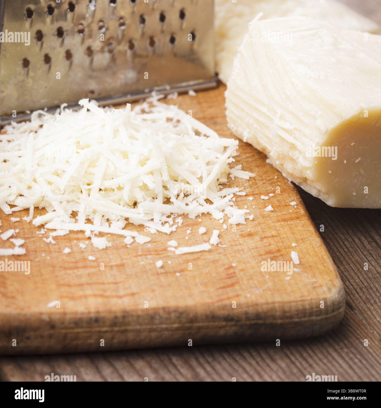 Parmigiano grattugiato con la grattugia su un tavolo Foto Stock