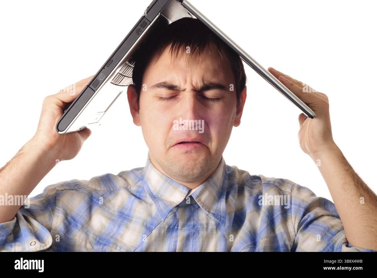 Un uomo tiene un portatile come un tetto di casa. Isolato su bianco. Programmatore frustrato guadagnato per la propria casa Foto Stock