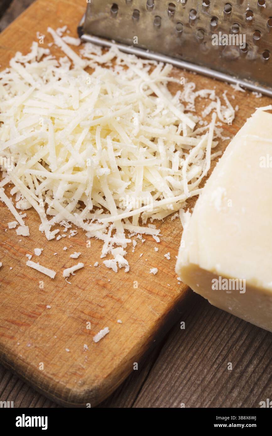 Parmigiano grattugiato con la grattugia su un tavolo Foto Stock