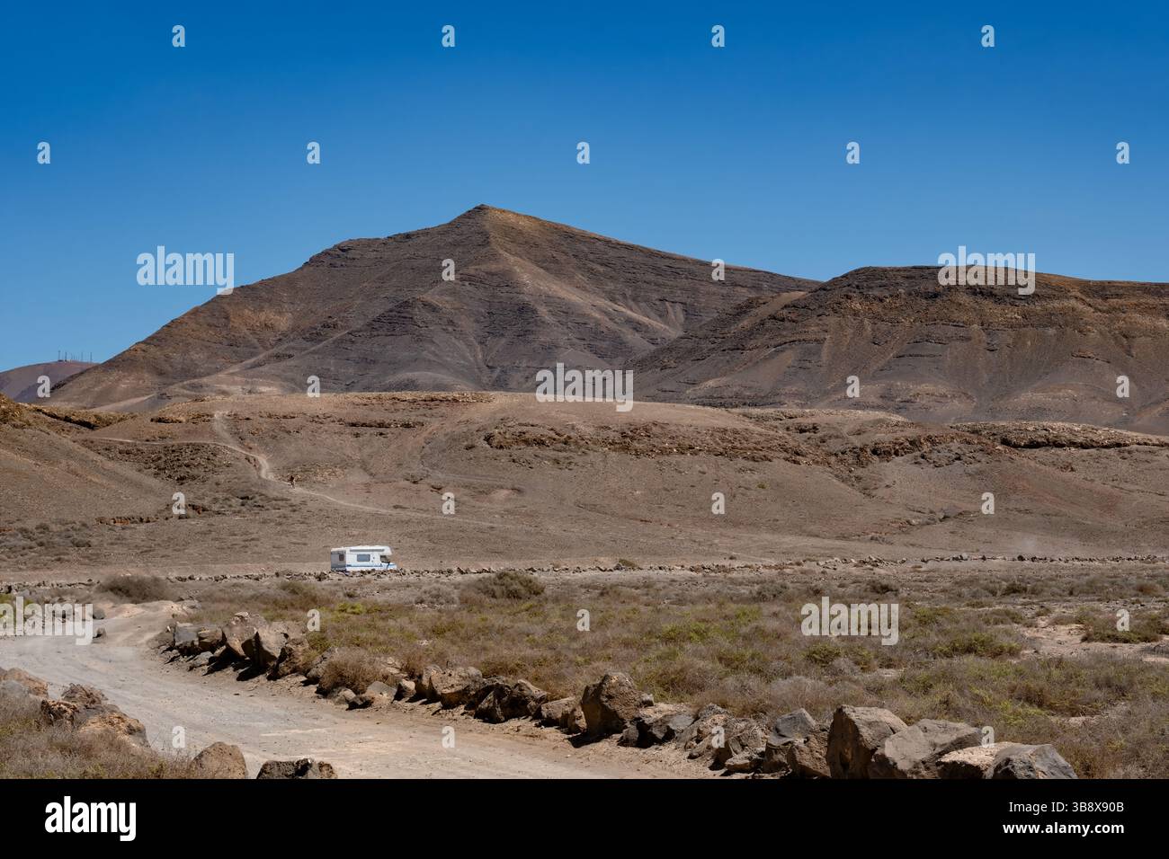 Lanzarote, Isole Canarie. Una vista su Hacha grande nel Parco naturale di Los Ajaches. Un camper sta guidando su una pista di polvere attraverso il paesaggio vulcanico Foto Stock