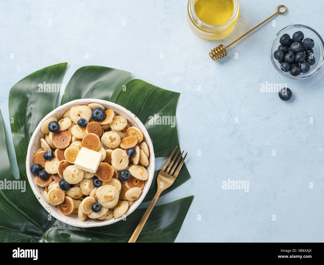 Cibo alla moda - pancake e cereali. Un mucchio di mini frittelle di cereali in bocce su sfondo blu. Copia spazio rimanente per il testo. Vista dall'alto o disposizione piatta Foto Stock