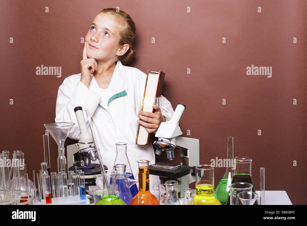 Riflessivo schoolgirl in piedi vicino a lavagna in laboratorio le classi in chimica Foto Stock