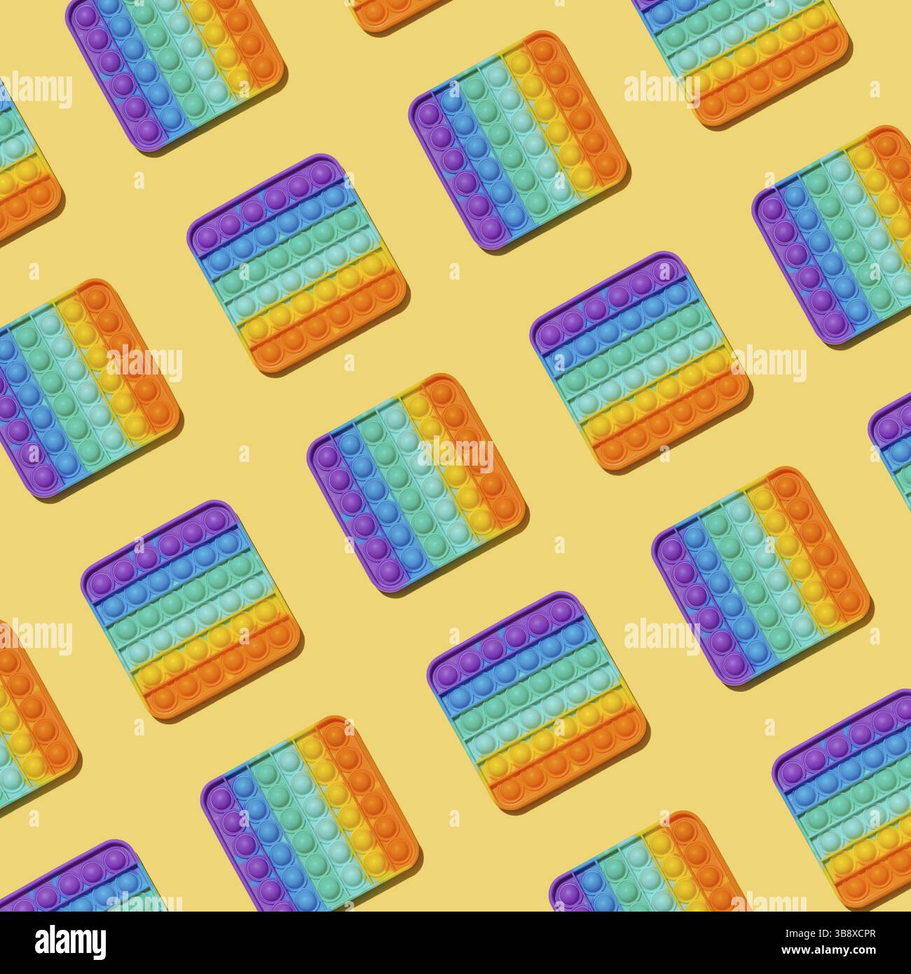 Motivo Popit su sfondo giallo. Popolare giocattolo in silicone colorato antistress pop it per bambini. Vista dall'alto. Semplice motivo a concavità Foto Stock